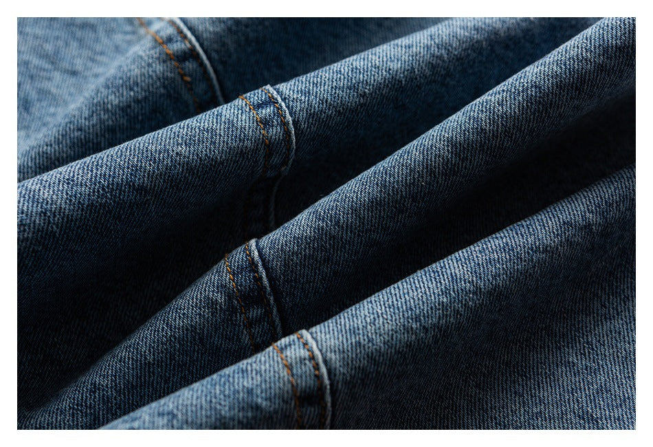 Close-up of folded blue denim fabric with visible twill texture and orange stitching.