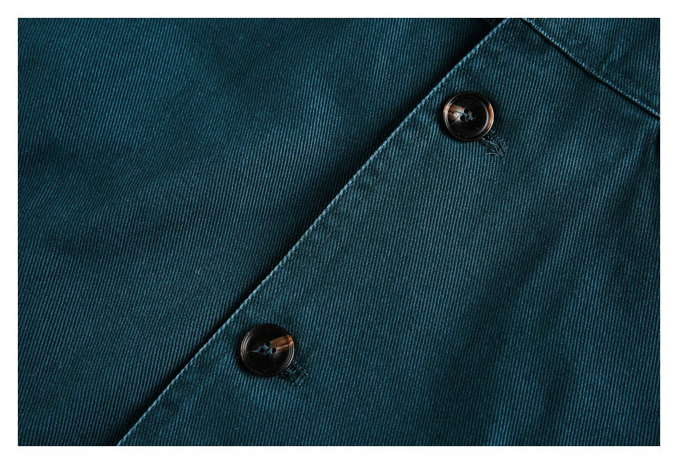Two dark buttons on overlapping panels of a teal twill garment.