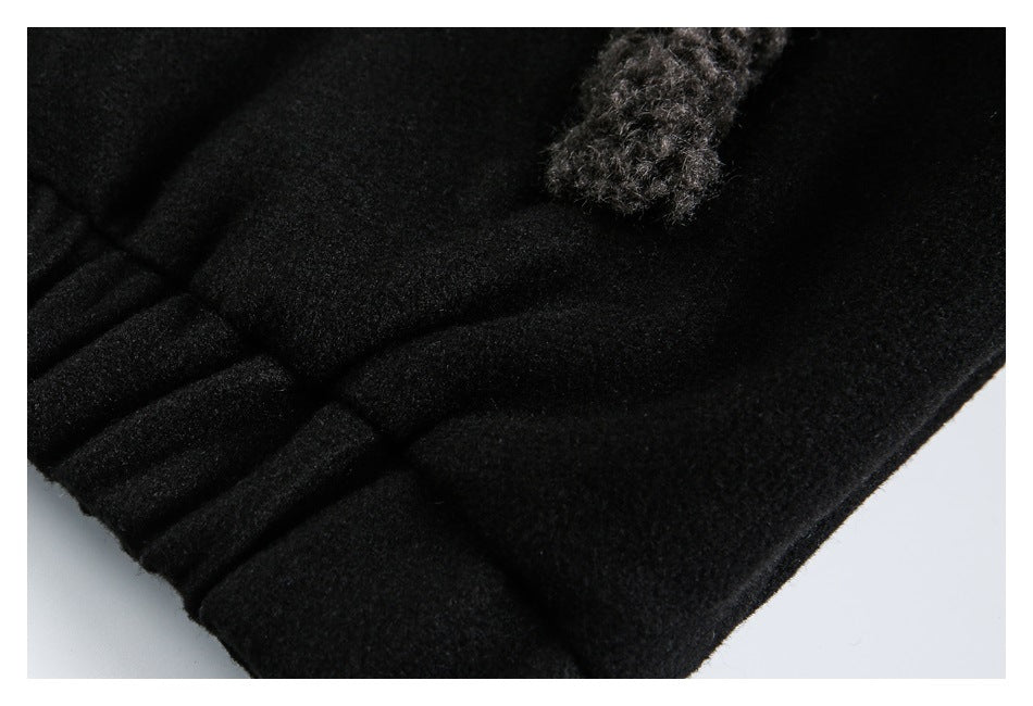 Close-up of a black garment's folded edge and pleats, with fuzzy charcoal trim near the top.