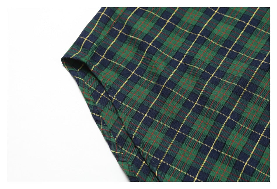 Close-up of a stitched edge and folded seam on the green and navy tartan shirt.