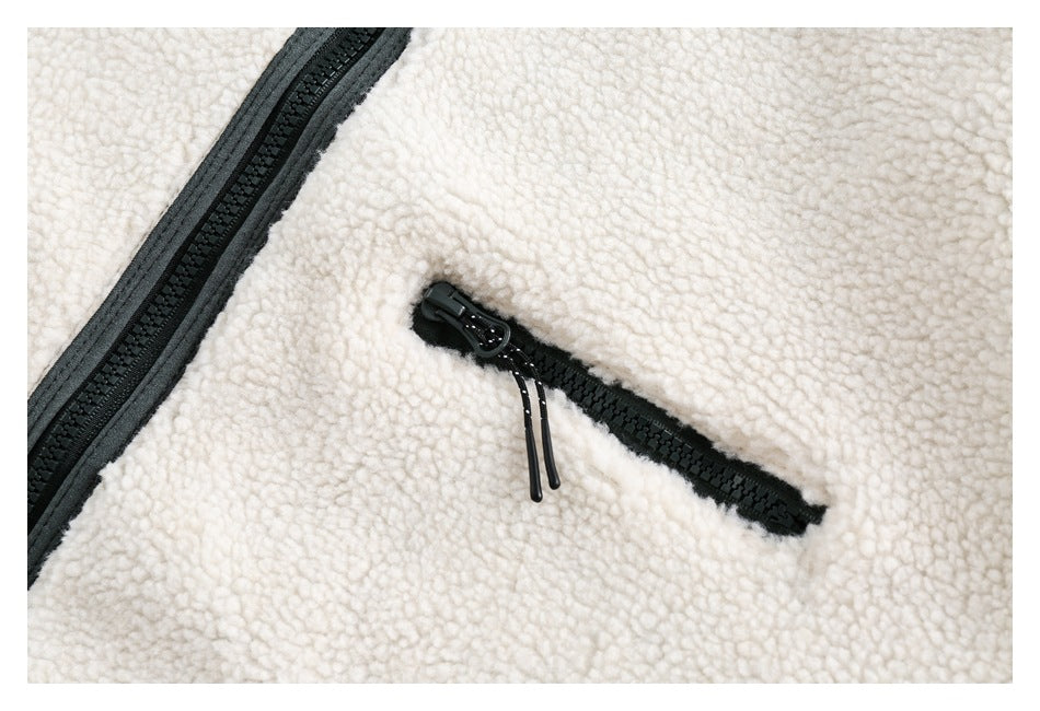 Close-up of the jacket's black-trimmed chest zipper pocket against ivory sherpa fabric.