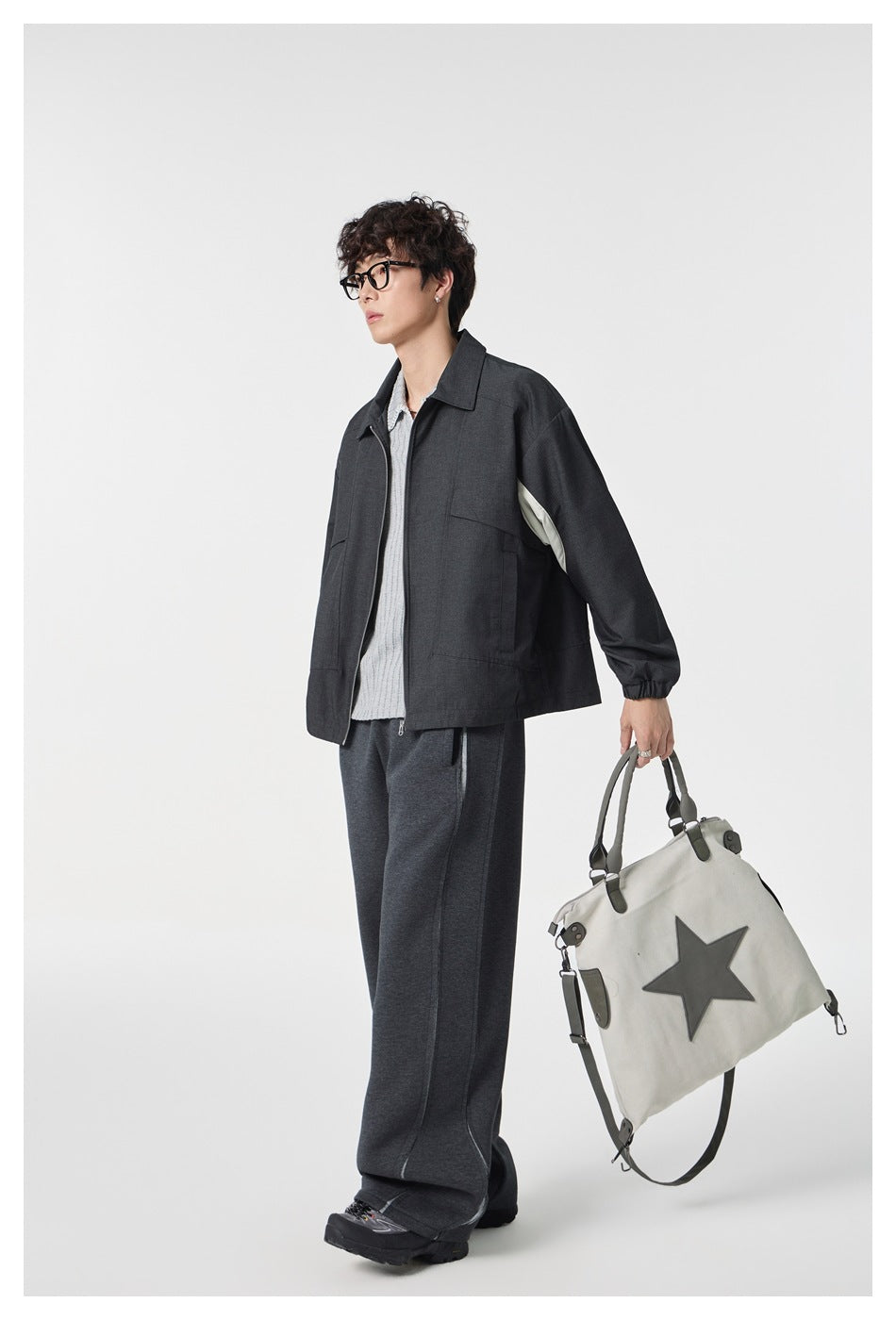 Model in a side view wearing a charcoal zip-front jacket with pale sleeve inserts and elastic cuffs.