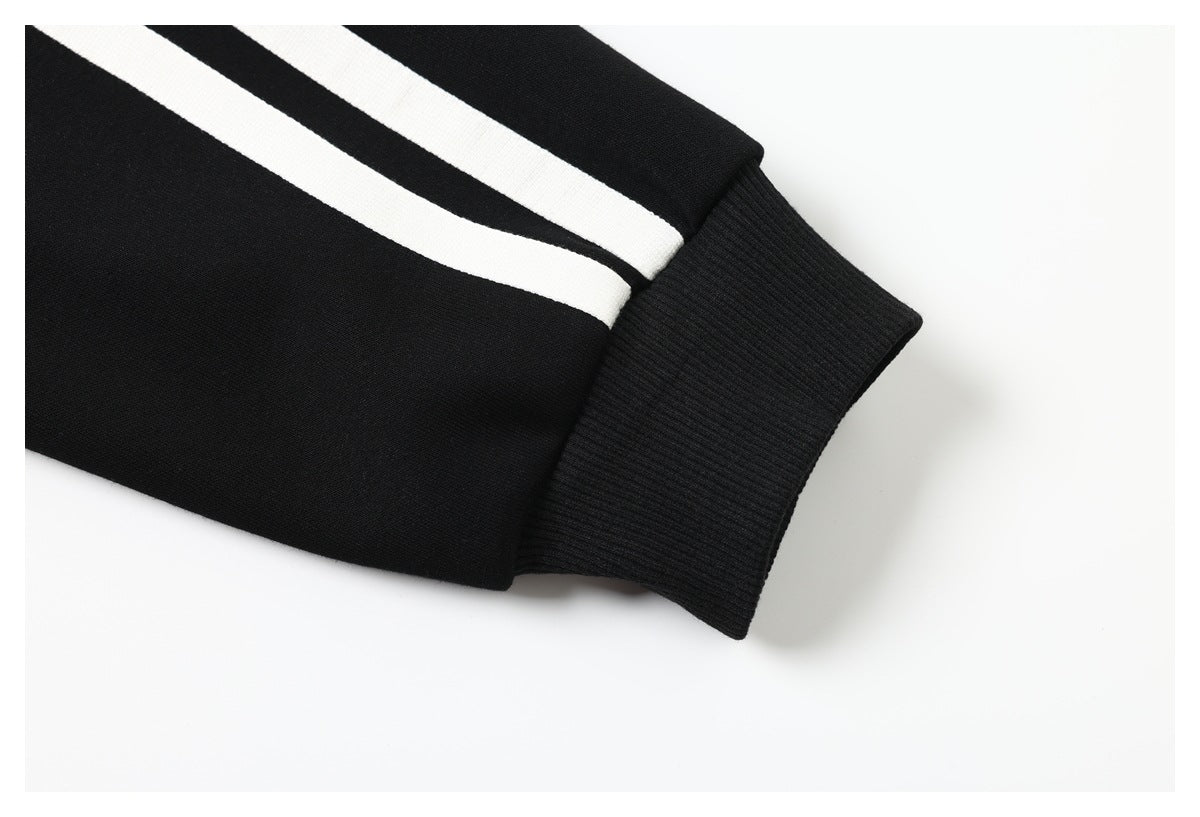 Close-up of a black sleeve with two white stripes and a ribbed black cuff.