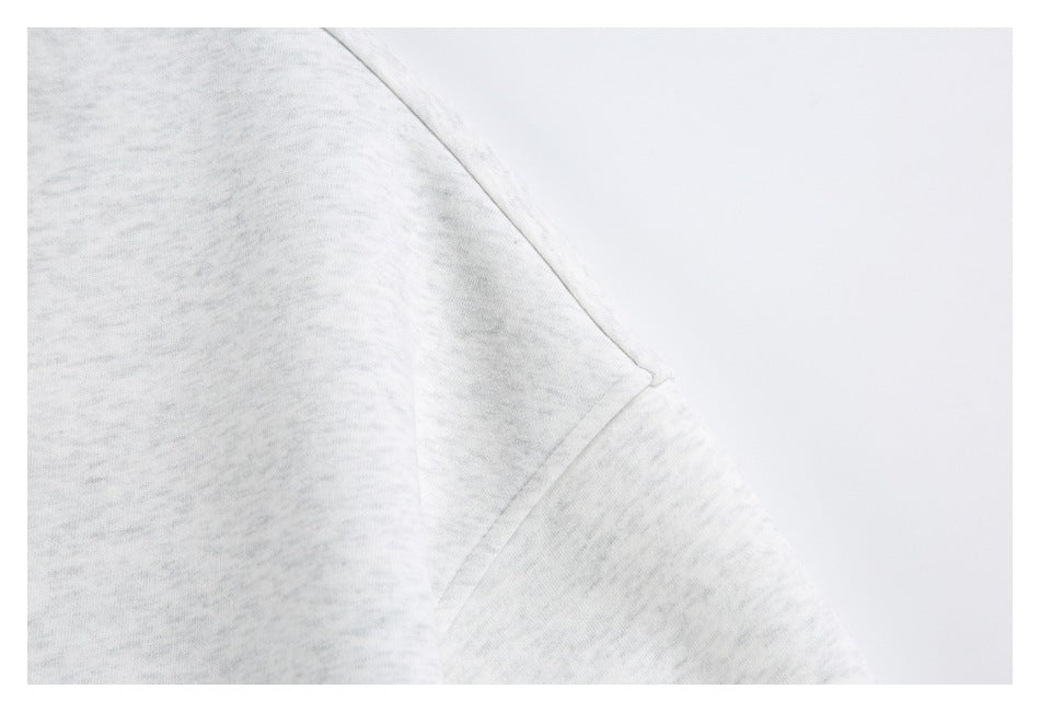 Close-up of the light gray top's shoulder and sleeve seam.