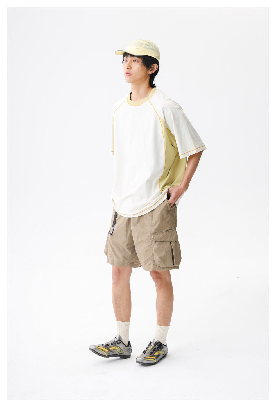 Model wearing a white and pale yellow color-block short-sleeve top with beige cargo shorts.