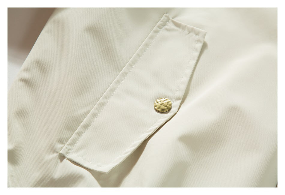 Close-up of an ivory garment pocket with a single gold-tone button.