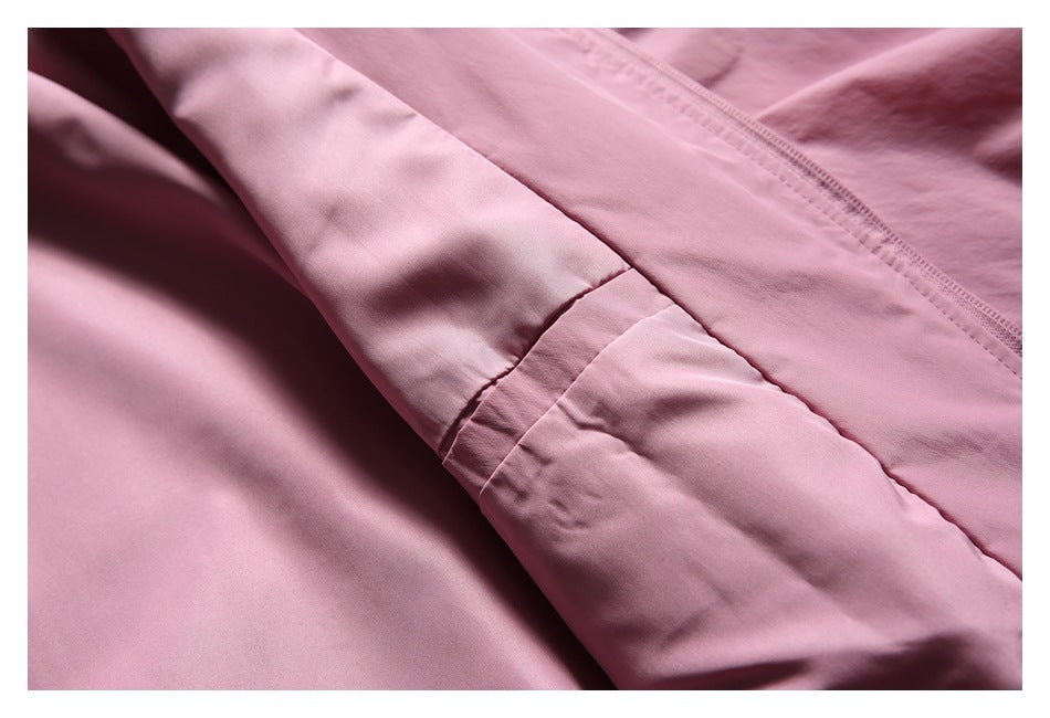 Close-up of pink garment construction, showing a stitched seam and zipper edge.