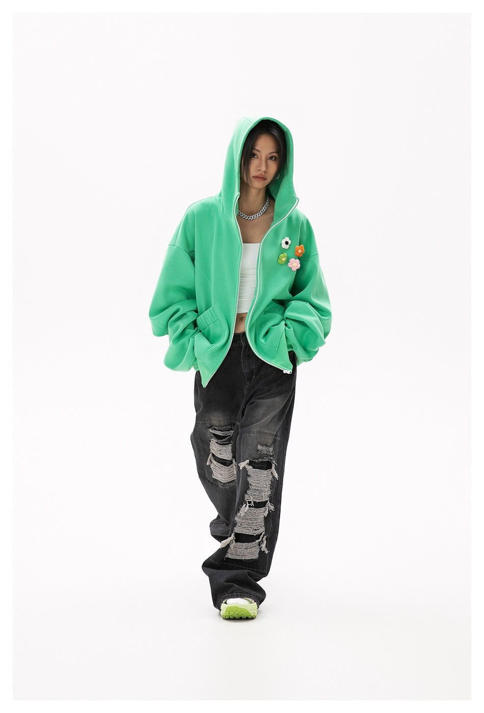 Full-length model wearing a mint-green floral-appliqué zip hoodie with distressed black jeans.