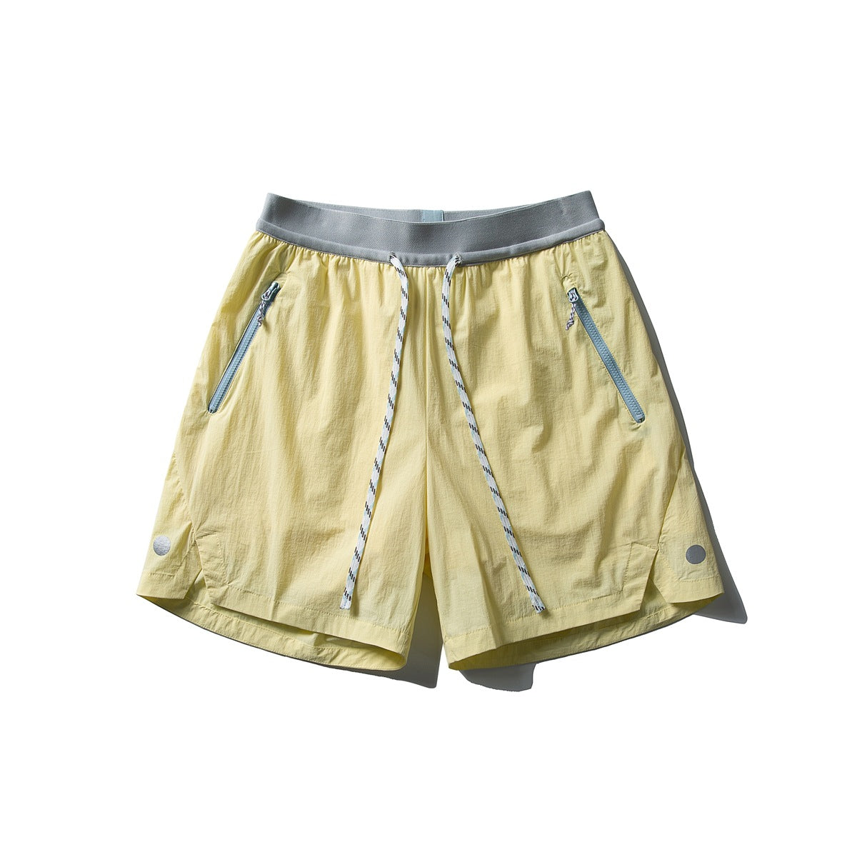 Light yellow drawstring shorts with gray waistband, pale blue zipper pockets and white rope cord, flat lay