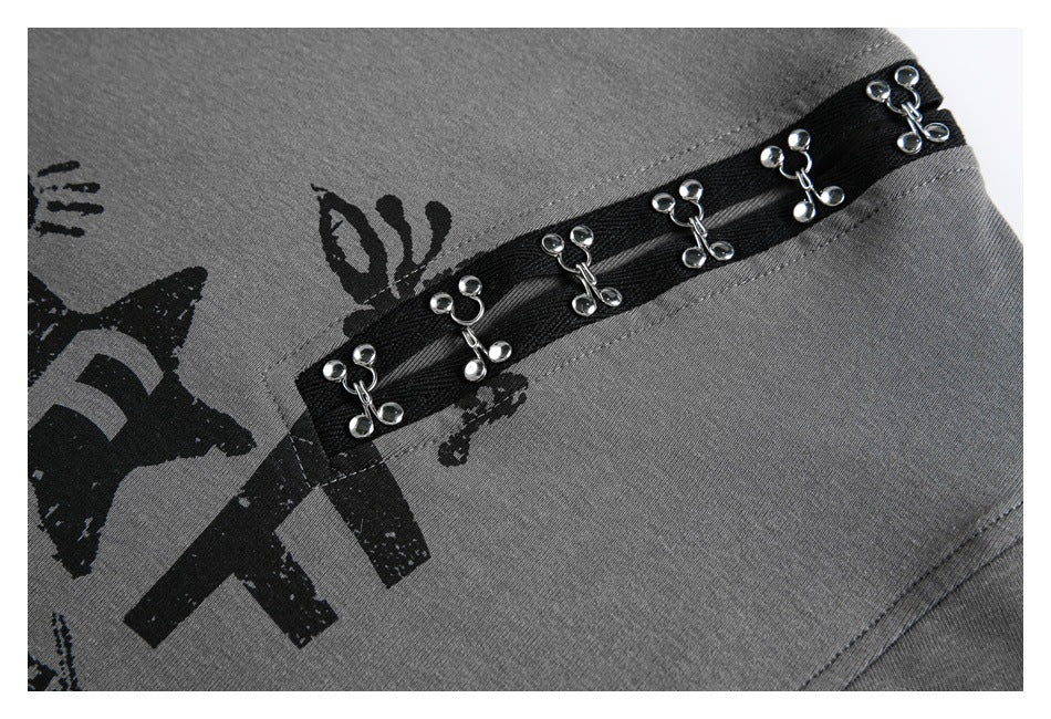 Close-up of gray fabric with a black printed graphic and a diagonal black band decorated with silver-toned charms.