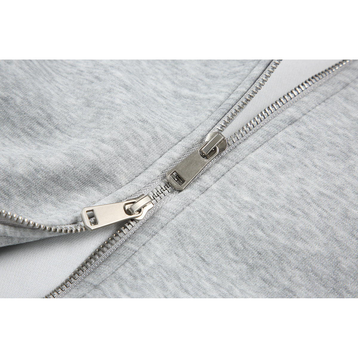 Close-up of the silver zipper and zipper pulls on a light gray hoodie.
