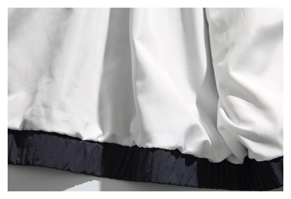 Close-up of a white garment hem above a wide black gathered band.
