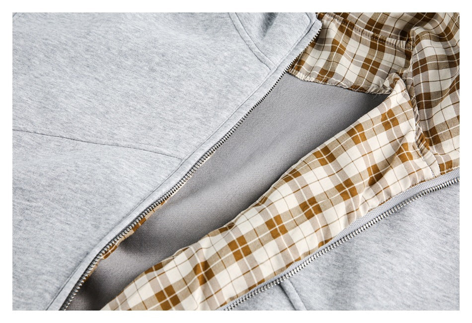 Close-up of an open heather gray jacket showing its zipper and brown-and-cream plaid inner collar lining.