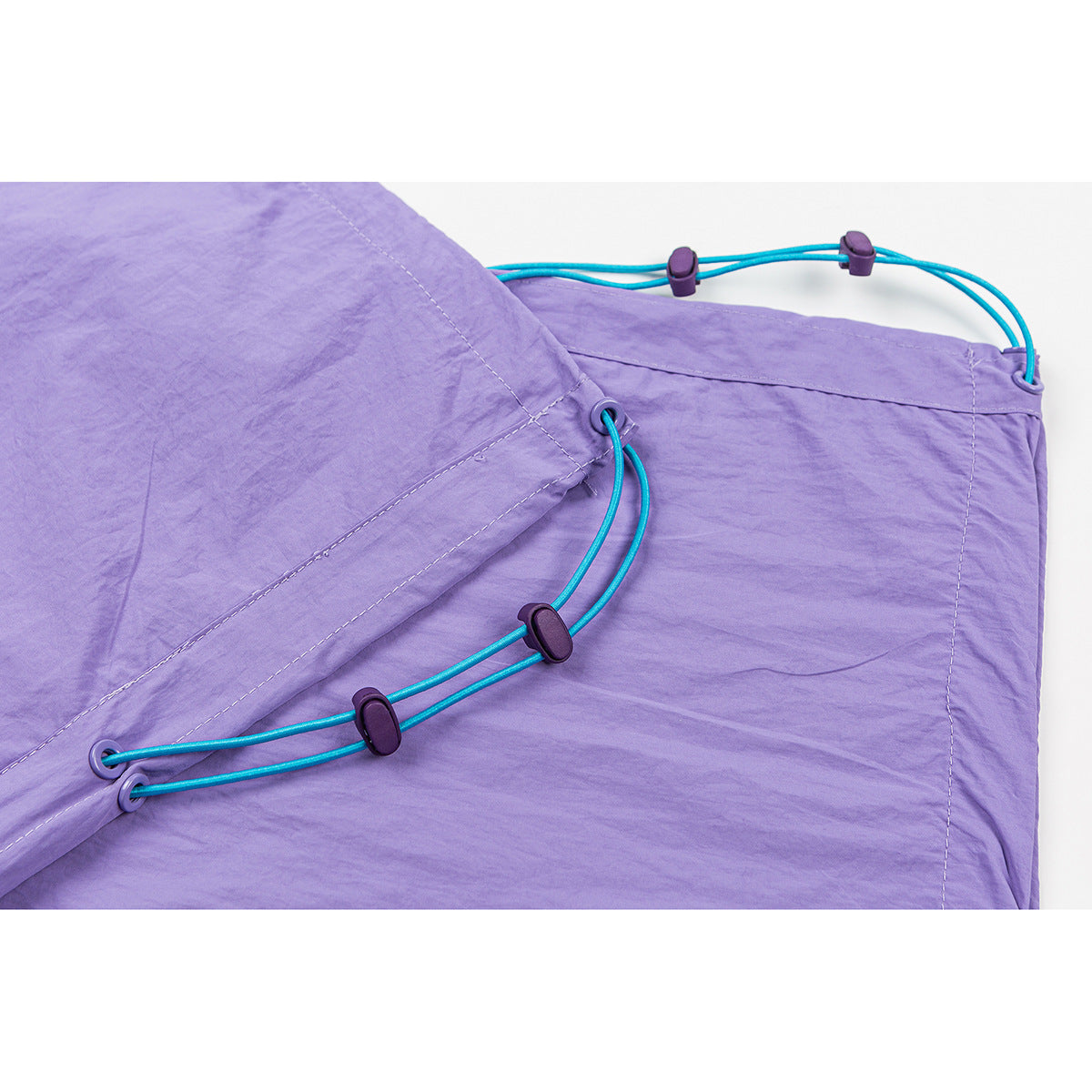 Close-up of turquoise adjustable cords and toggles along the side of lavender pants.