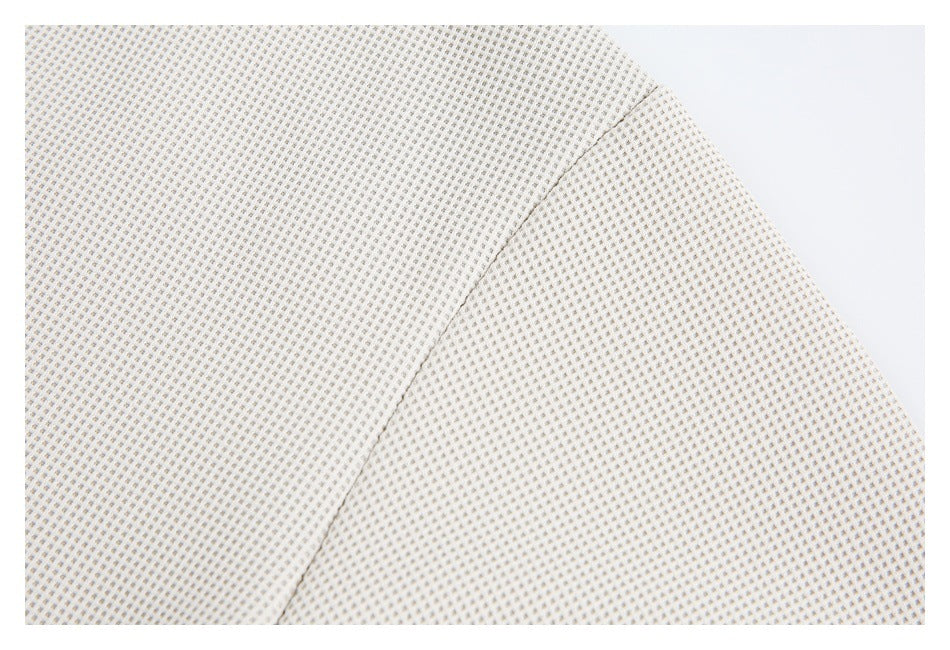 Close-up of cream fabric with a small repeating raised pattern and a diagonal seam.
