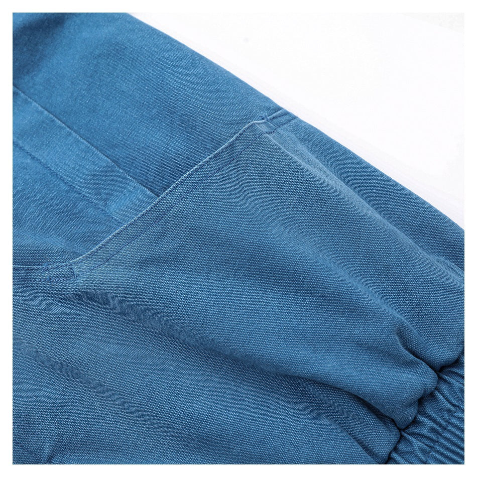 Close-up of a blue jacket pocket opening and stitched seams near the gathered hem.