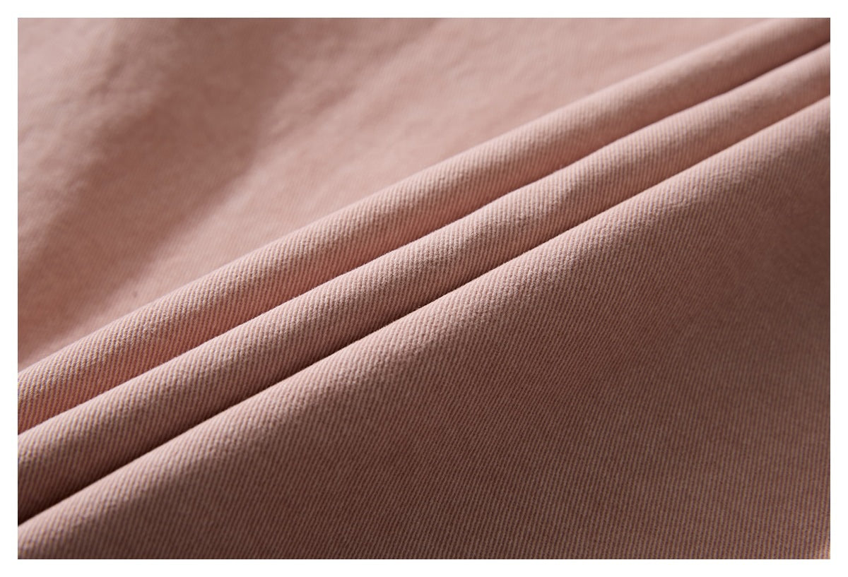 Close-up of dusty mauve fabric draped in folds, showing a fine diagonal ribbed texture.