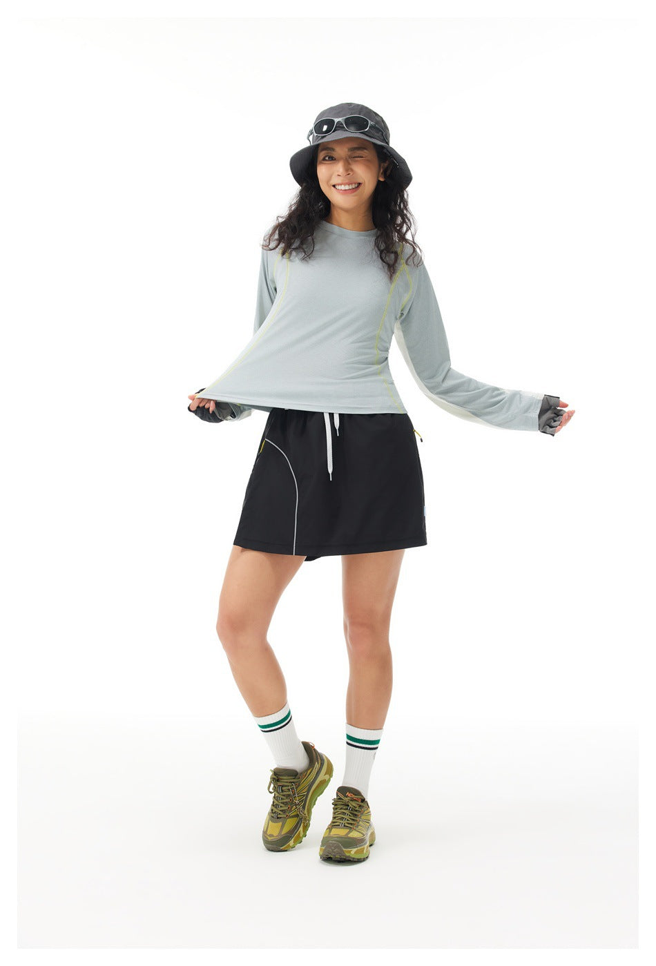 Model displays a pale gray long-sleeve top with lime seams and a black skort against a white background.