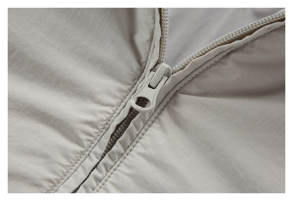 Close-up of the light gray-beige jacket's front zipper and stitching.