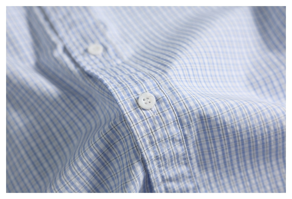 Close-up of white buttons and the placket on a blue-and-white checked shirt.