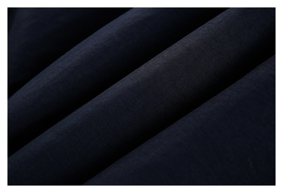 Close-up of dark navy-black fabric arranged in diagonal folds, showing its fine weave.