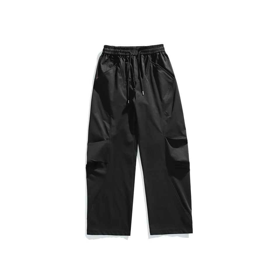Black wide-leg pants flat lay with drawstring elastic waist, curved leg seams and large pleated thigh pockets