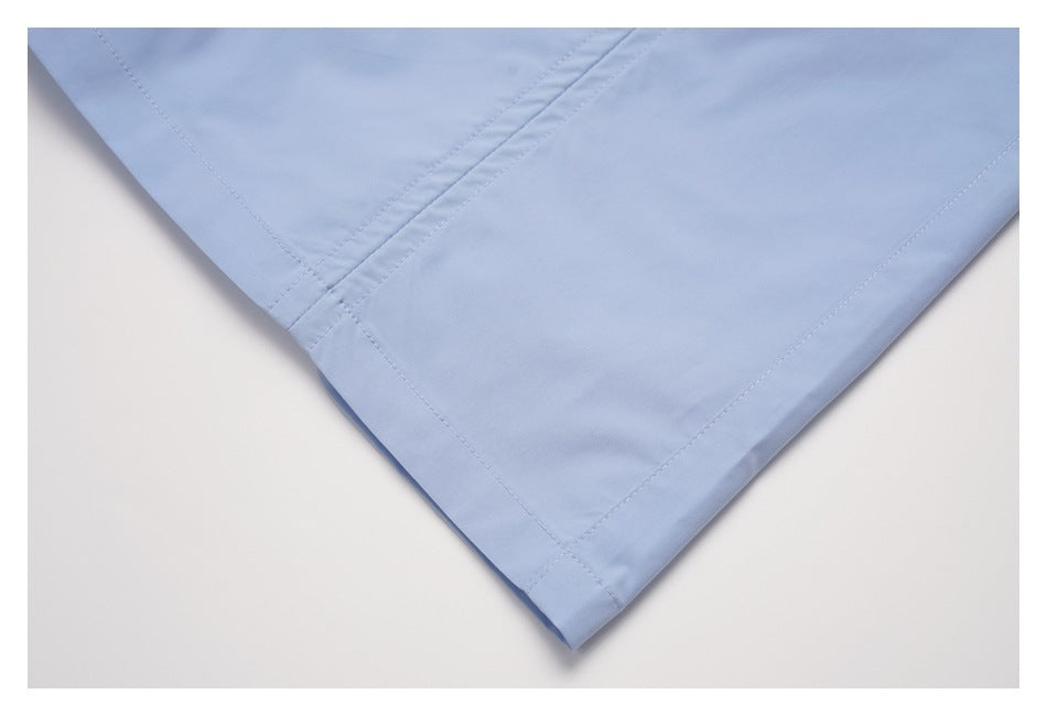 Close-up of a pointed corner and double-stitched seams on light blue garment fabric.
