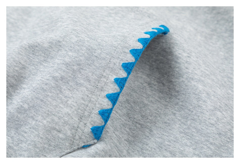 Close-up of bright blue triangular stitching along an edge of heather gray fabric.