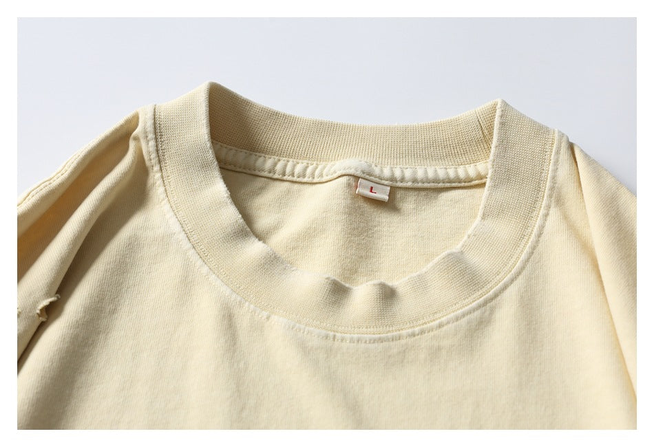 Close-up of a cream T-shirt's ribbed crew neckline and inner label marked L.