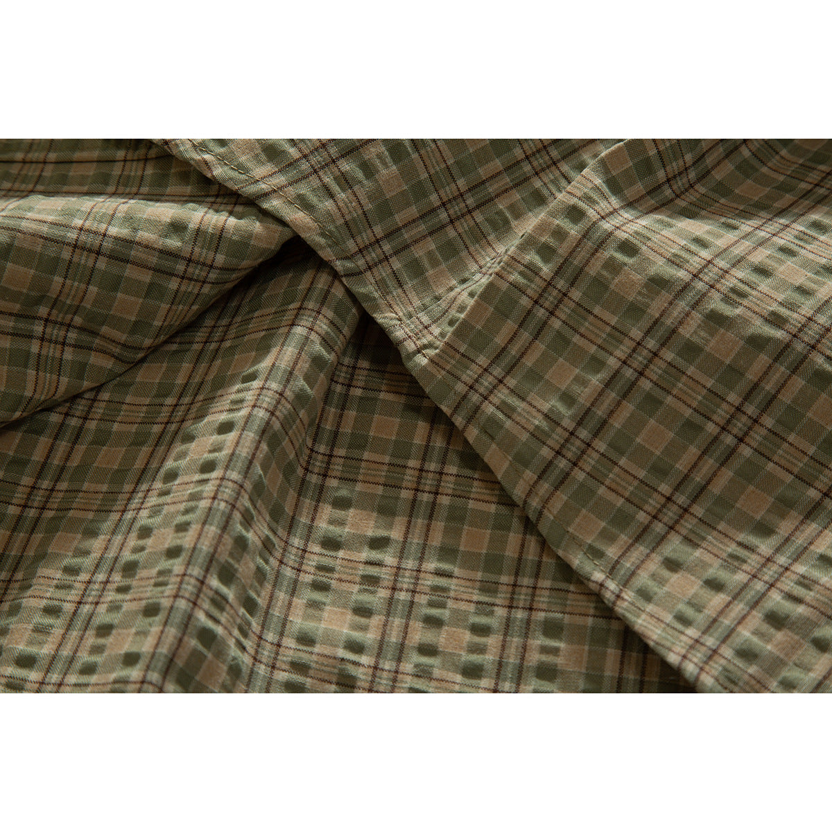 Close-up of overlapping olive and tan plaid shirt fabric with intersecting stripe patterns.