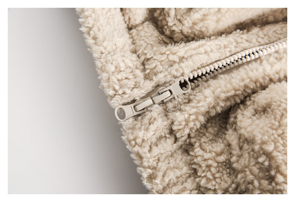 Close-up of a light beige plush jacket with a pale zipper and pull.