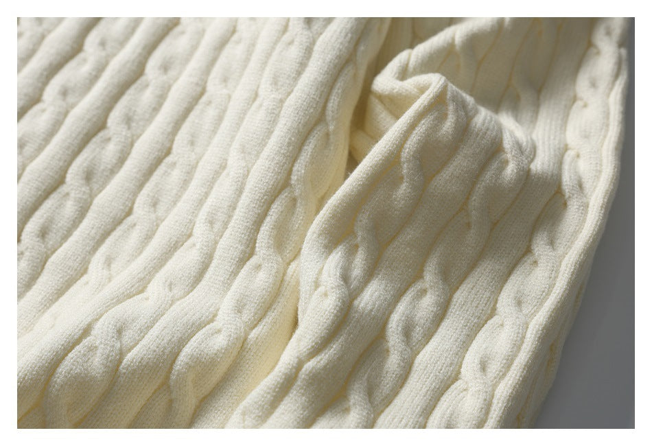 Angled close-up showing the ivory sweater's raised cable-knit texture and sleeve.