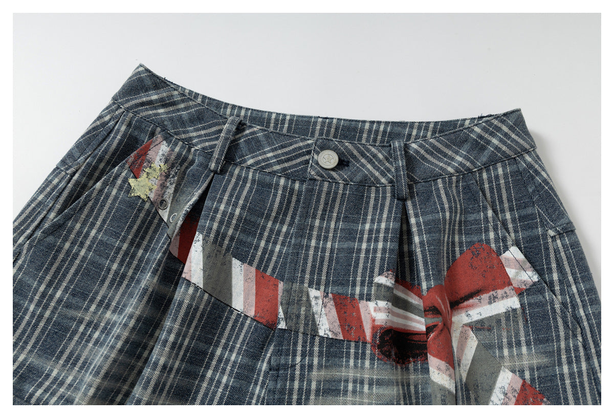 Close-up of blue-gray plaid shorts waistband and fly with a distressed red, white, and gray graphic.