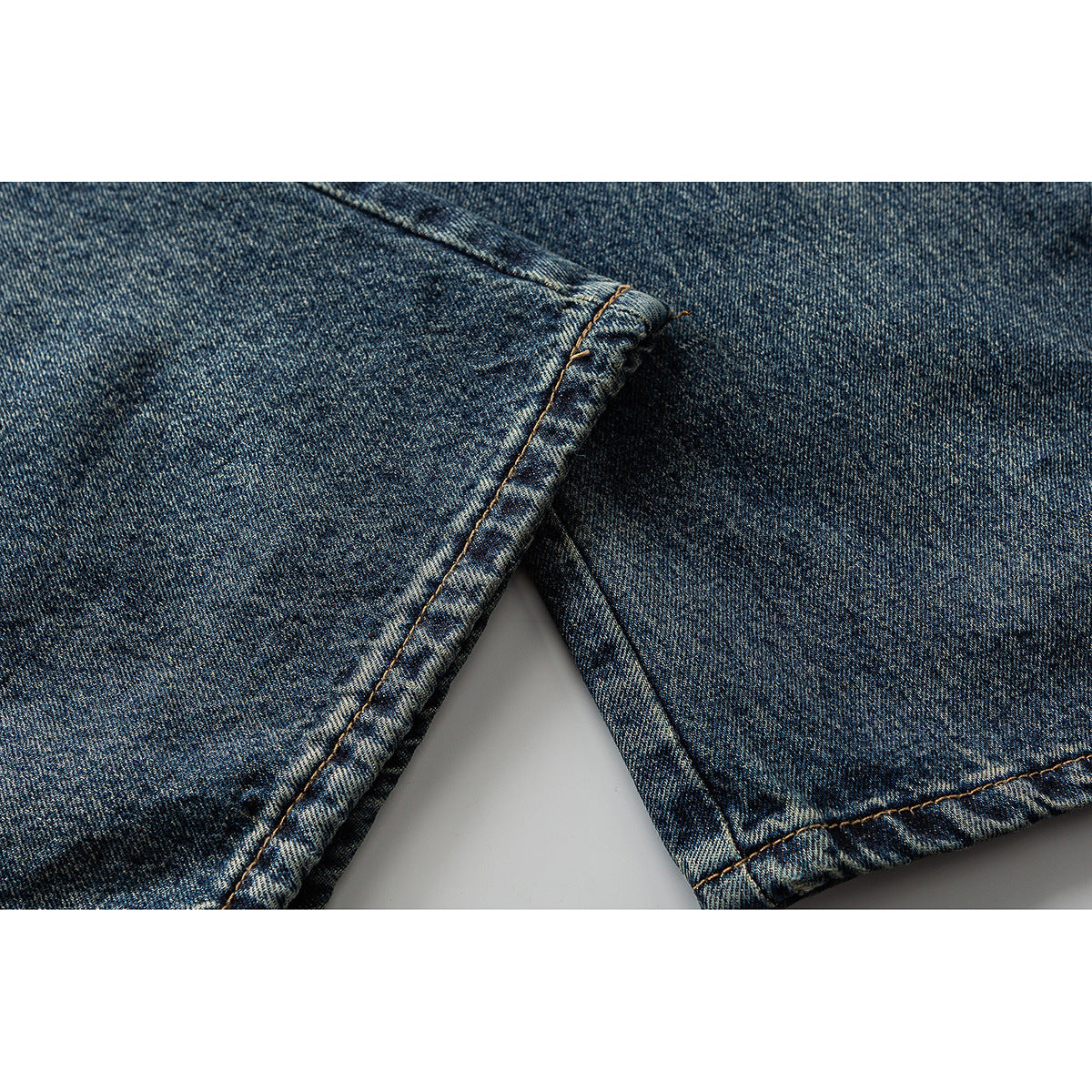 Close-up of blue washed jeans legs and their double-stitched hems.