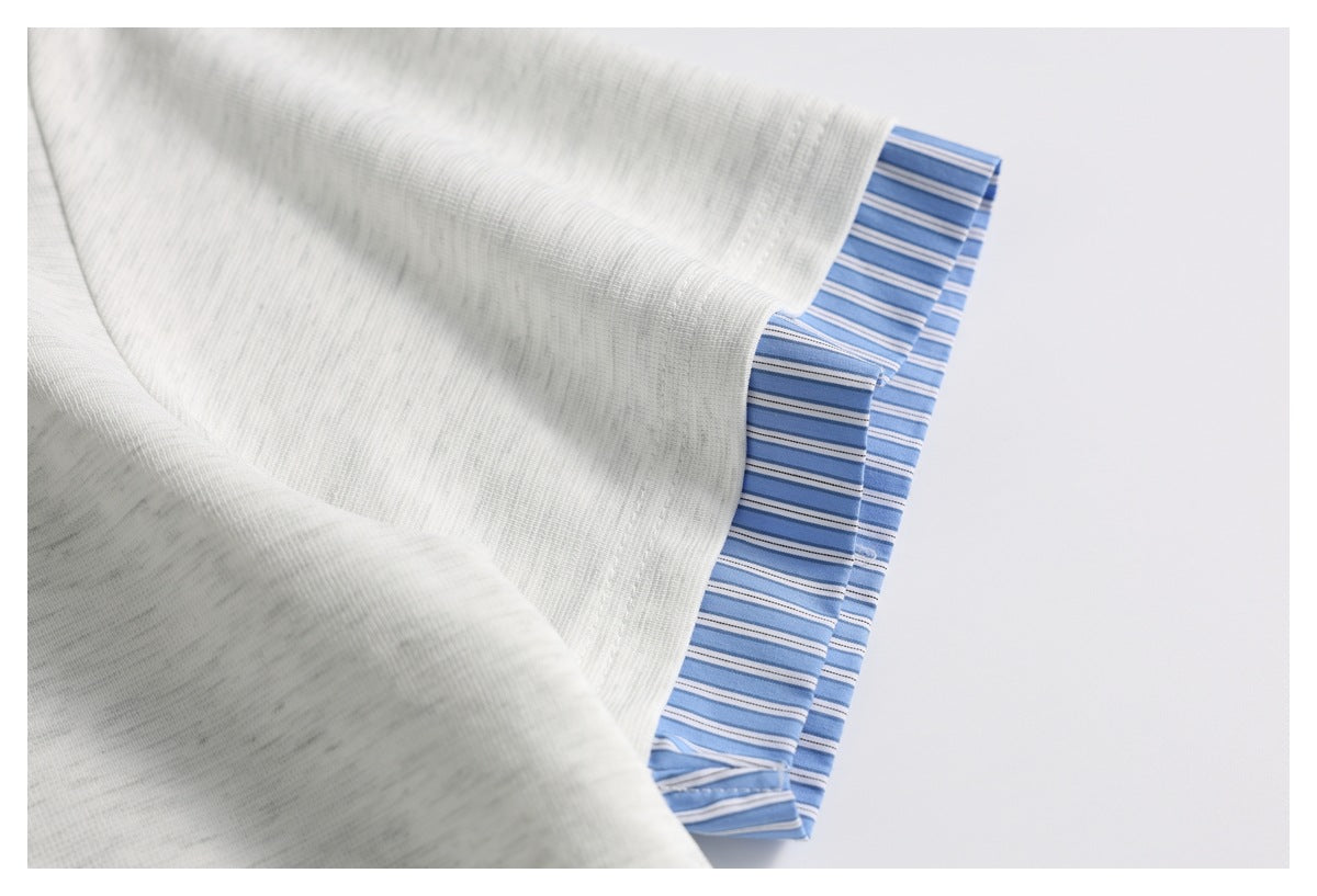 Close-up of light gray fabric folded over blue-and-white striped fabric.