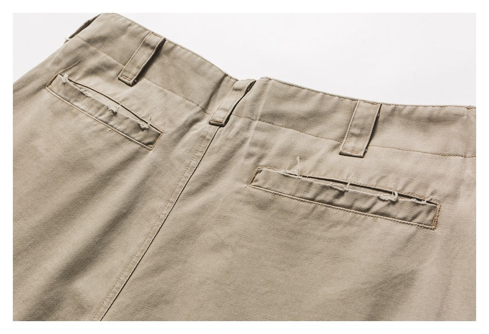 Close-up of the back of beige trousers, showing the waistband, belt loops and two welt pockets.