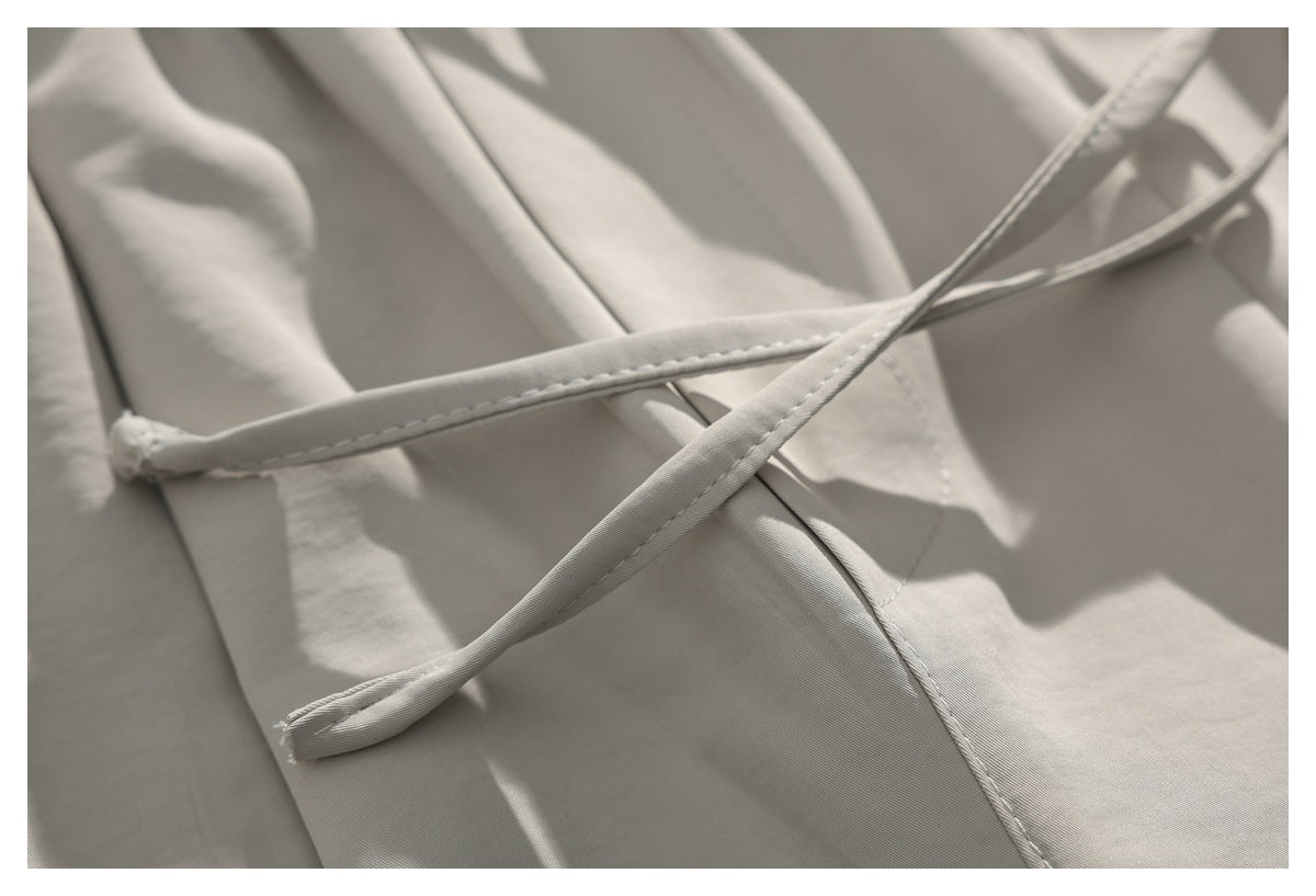Close-up of the matching drawstrings crossing over the light beige trouser fabric.