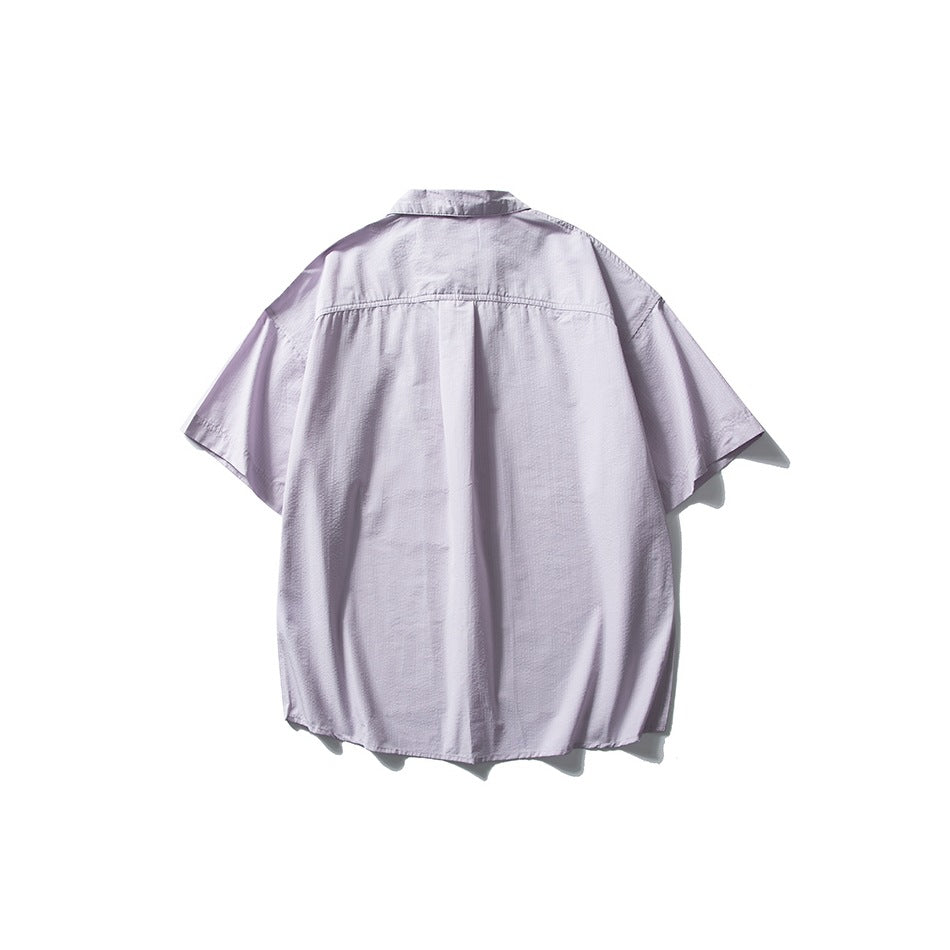 Back view of a pale lavender oversized short-sleeve button-up shirt with a center pleat.