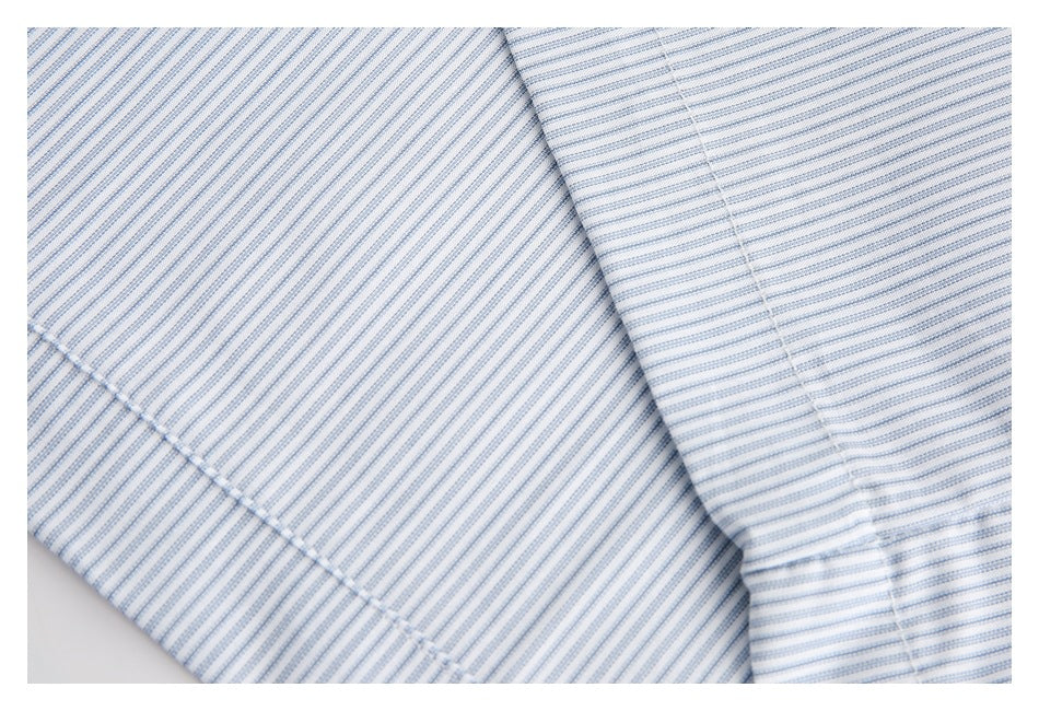 Close-up of fine blue-and-white striped fabric with a folded seam and stitched edge.