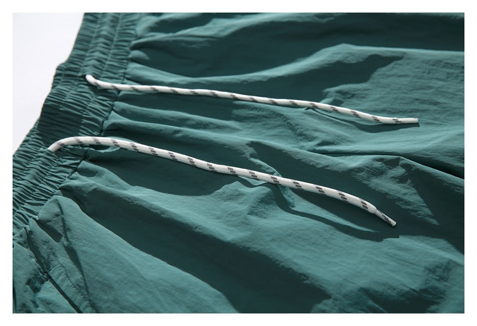 Close-up of the teal shorts’ white patterned drawstrings against the fabric.