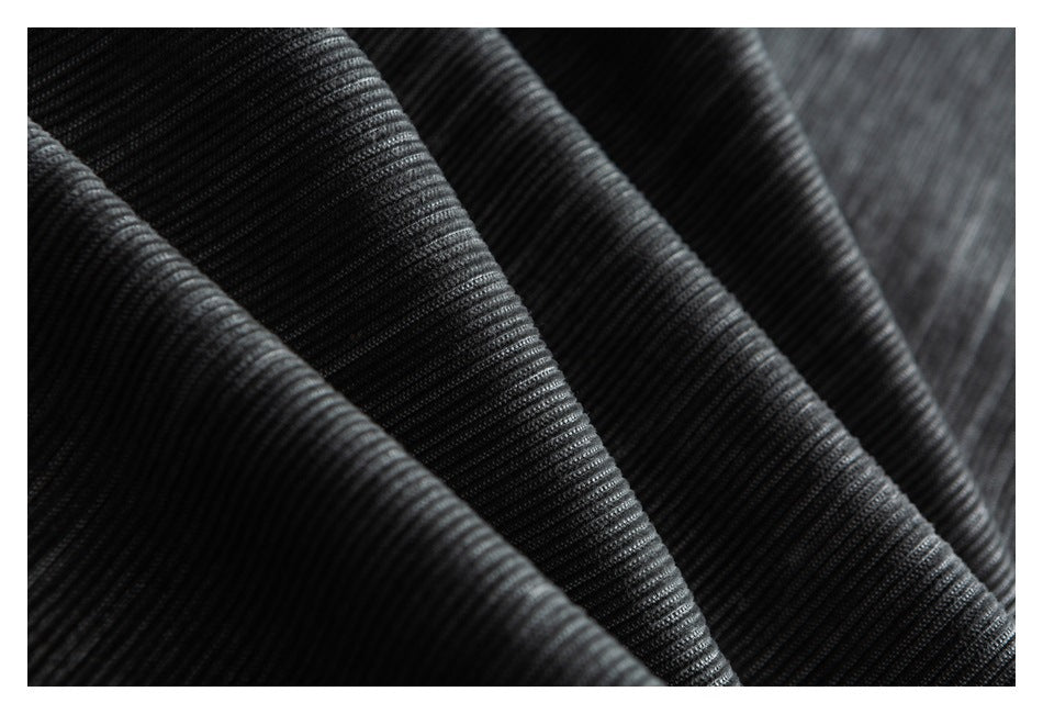 Macro view of the dark gray, finely ribbed striped trouser fabric.
