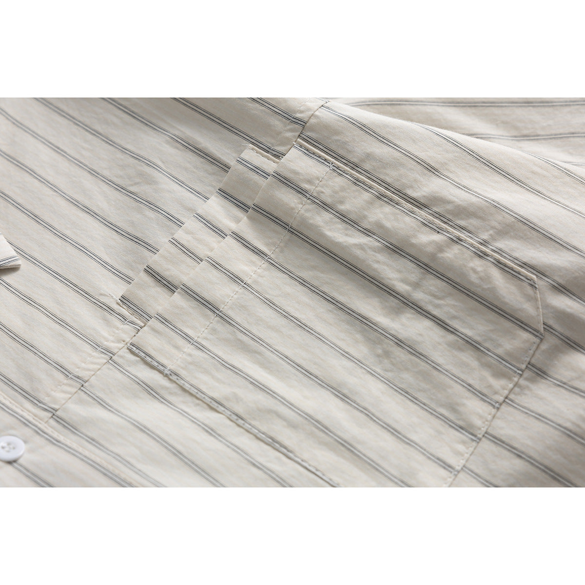 Close-up of a cream shirt with fine gray stripes, showing its chest pocket and stitching.