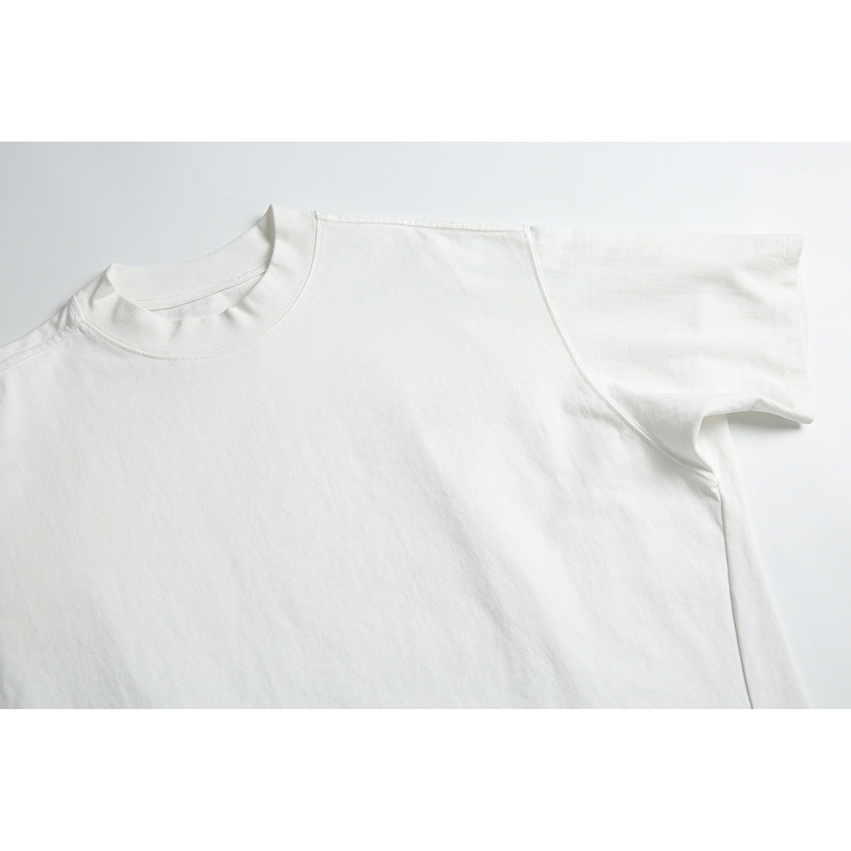 Close-up of a plain white T-shirt showing its crew neck, shoulder seam, and short sleeve.