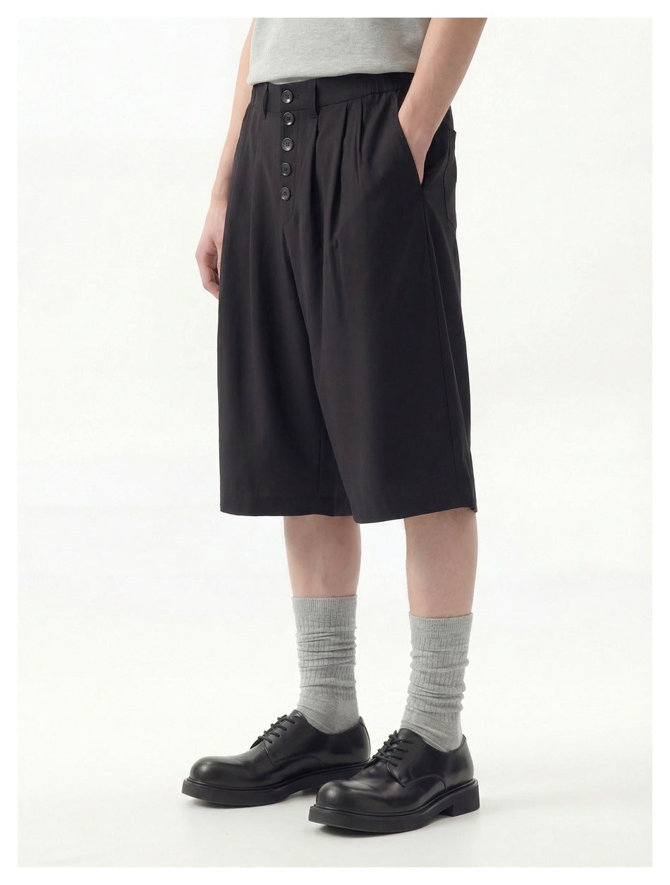 Model in black wide-leg button-front shorts with gray ribbed socks and black lace-up shoes, side-front view
