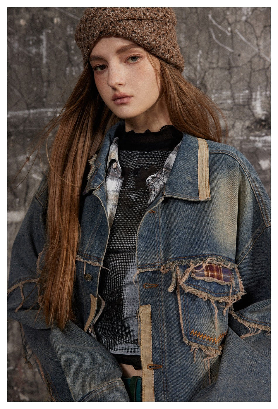Close view of a model in a distressed blue denim jacket with frayed plaid patch pockets and tan trim.
