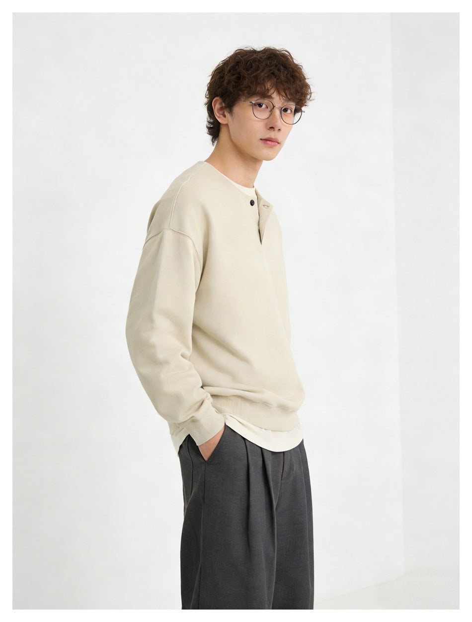 Model wearing a light cream long-sleeve top with a short button placket and dark trousers.
