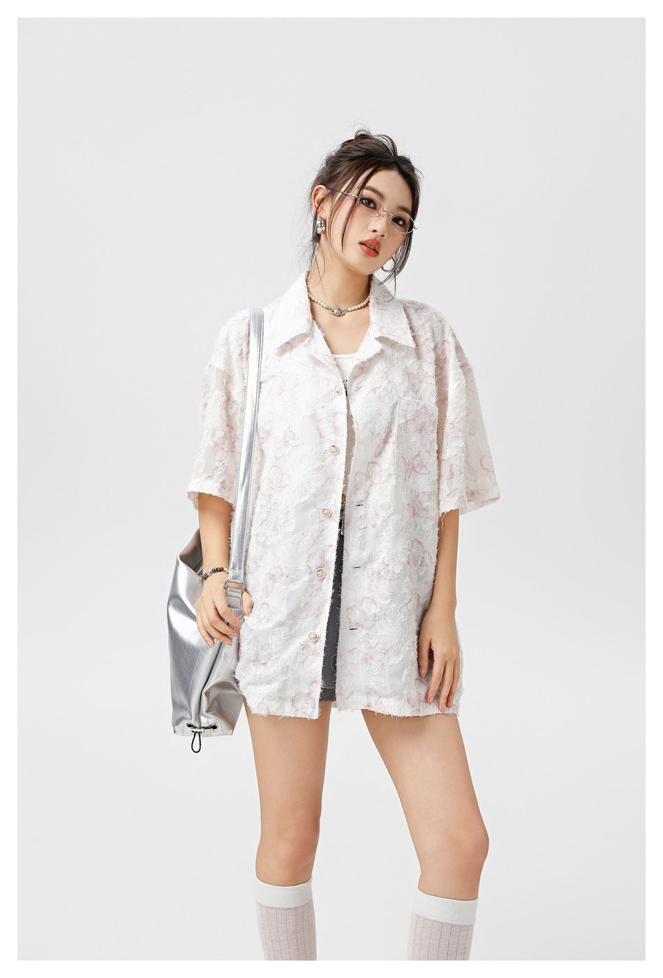 Model wearing an oversized ivory short-sleeve button-up shirt with a subtle pale pink floral pattern.