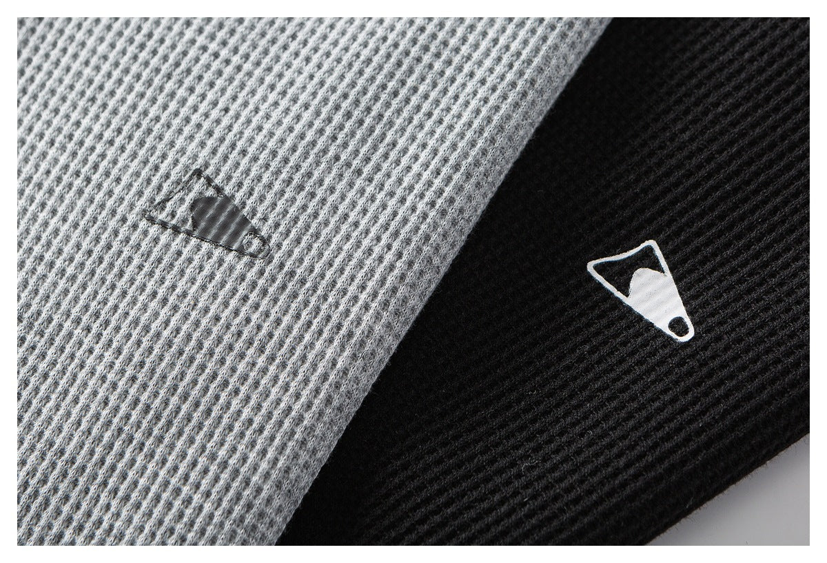 Close-up of gray and black waffle-knit fabric panels, each with a small contrasting emblem.