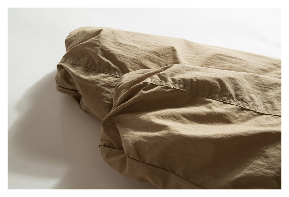 Close-up of a tan jacket sleeve and stitched seam against a white background.