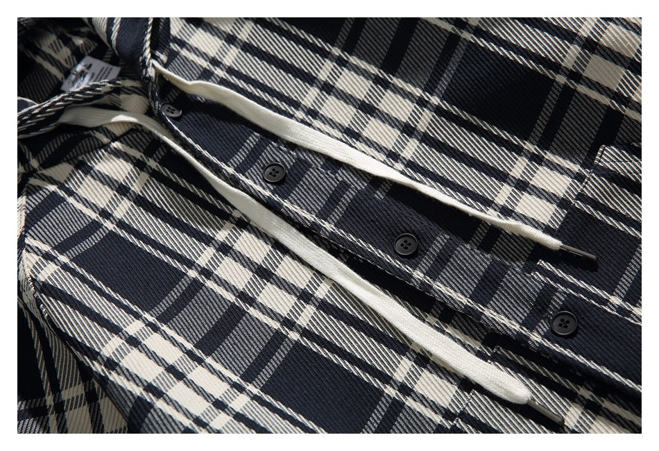 Close-up of the plaid shirt jacket's black buttons and cream drawcords along the front placket.